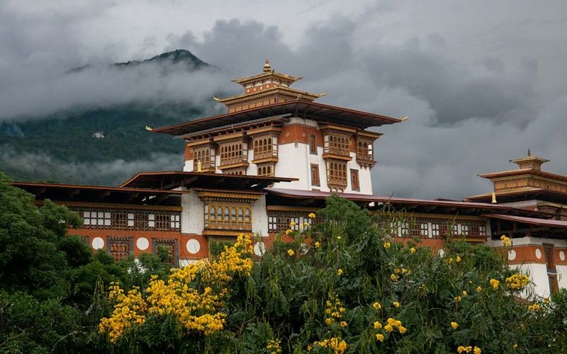 Traditional Bhutanese dzong below cloudy mountains